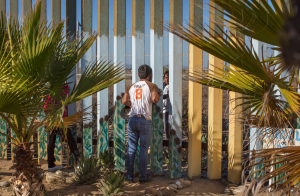 Through the Wall Winner single image in Border category A young man speaks to a family member through the border fence at Friendship Park a meeting place on the border between Tijuana, Mexico and San Diego, California. For many families separated by immigration status, it is the only way that they can see their loved ones in person pic Griselda San Martin