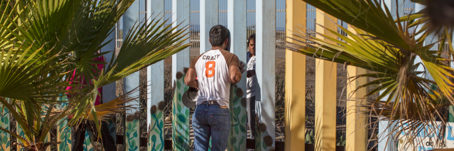 Through the Wall Winner single image in Border category A young man speaks to a family member through the border fence at Friendship Park a meeting place on the border between Tijuana, Mexico and San Diego, California. For many families separated by immigration status, it is the only way that they can see their loved ones in person pic Griselda San Martin